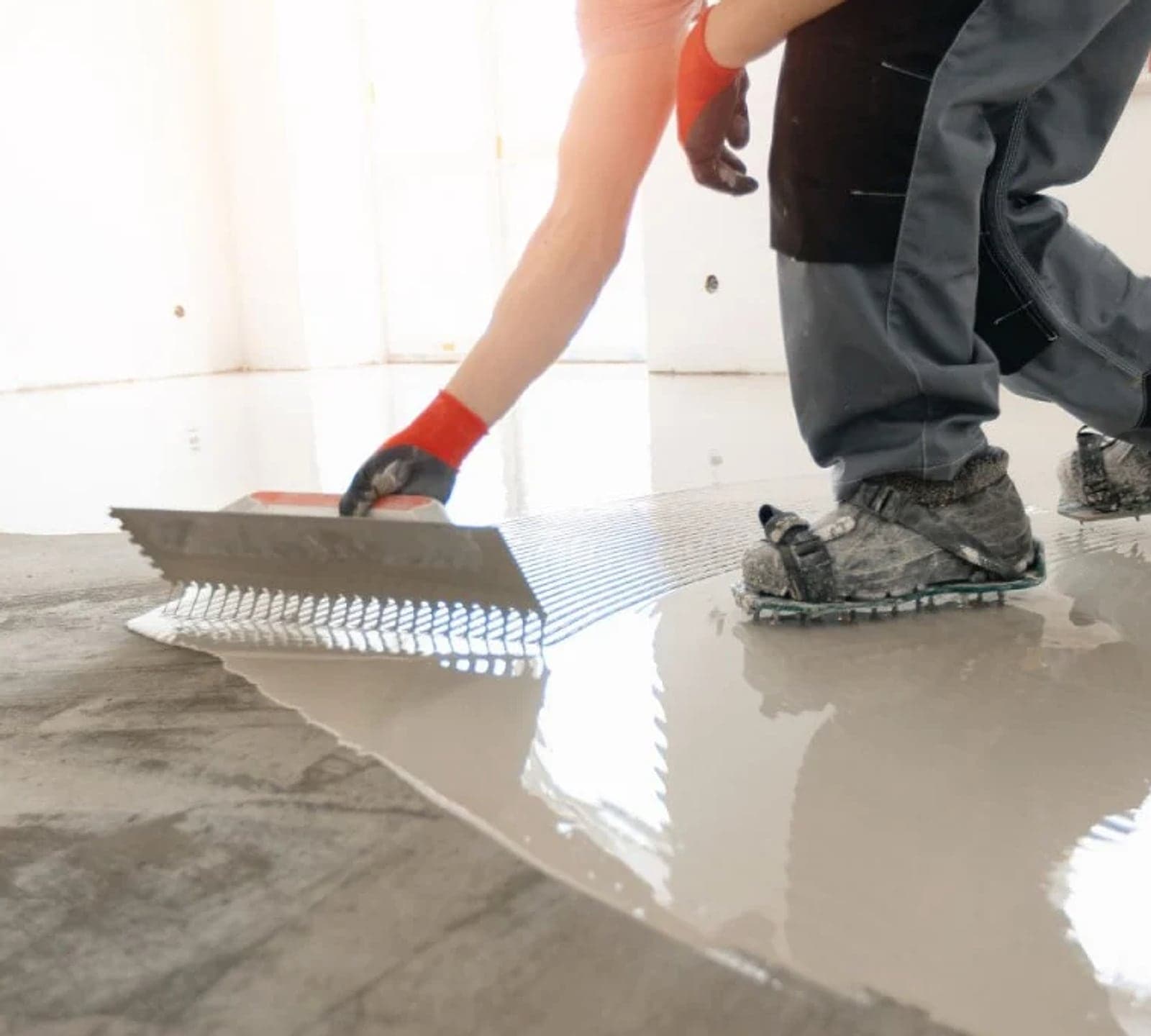 Self-leveling compound being spread flat across a concrete subfloor with a trowel